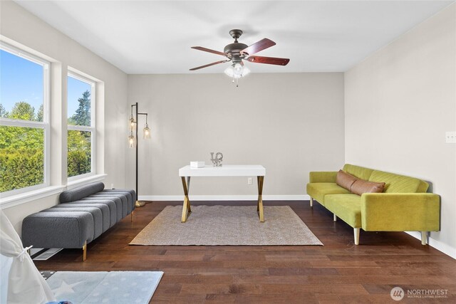 living area with a ceiling fan, wood finished floors, and baseboards