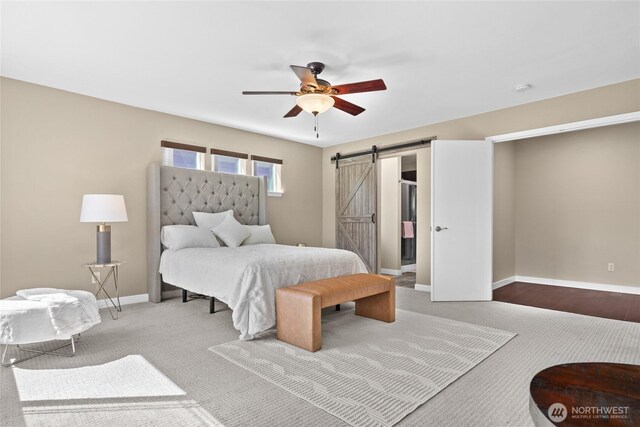 bedroom with a barn door, carpet flooring, baseboards, and a ceiling fan