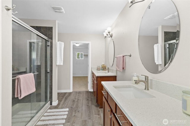 bathroom with a shower stall, wood finished floors, vanity, and baseboards