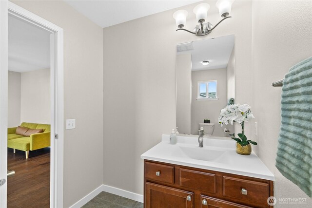 bathroom with vanity, a chandelier, and baseboards