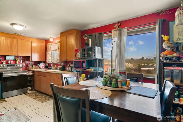 kitchen with stainless steel electric range, a sink, light countertops, brown cabinets, and black microwave
