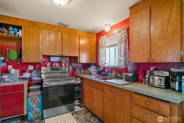 kitchen with stainless steel range with electric stovetop, a sink, brown cabinetry, light countertops, and light floors