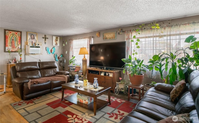 living area with a textured ceiling, wood finished floors, and a wall mounted air conditioner