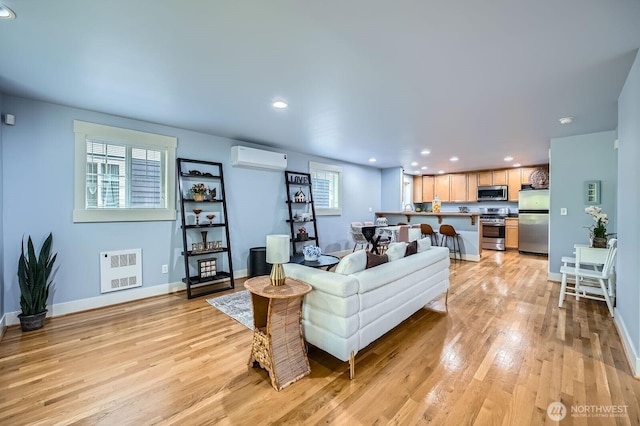 living area featuring an AC wall unit, light wood-style floors, recessed lighting, and baseboards
