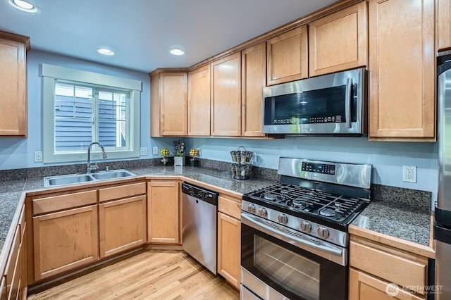 kitchen with stainless steel appliances, a sink, tile counters, recessed lighting, and light wood-type flooring