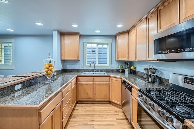 kitchen with stainless steel appliances, a sink, light wood-style floors, tile counters, and recessed lighting