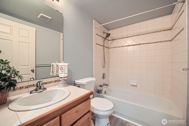 bathroom featuring toilet, vanity, shower / bath combination, wood finished floors, and tasteful backsplash