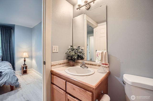 half bath with wood finished floors, toilet, and vanity