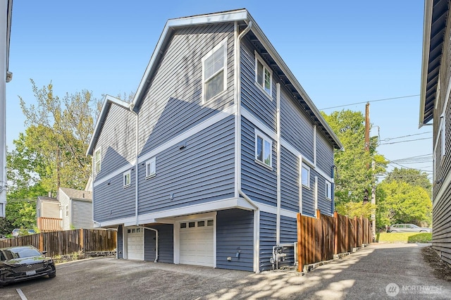 view of home's exterior featuring a garage, fence, and asphalt driveway