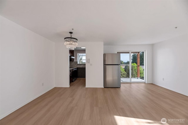 12050 15th Ave NE Unit 404, Seattle, WA 98125 - unfurnished living room with light wood-style floors, baseboards, and a chandelier