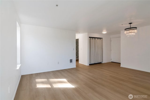12050 15th Ave NE Unit 404, Seattle, WA 98125 - spare room with wood finished floors, a chandelier, and baseboards