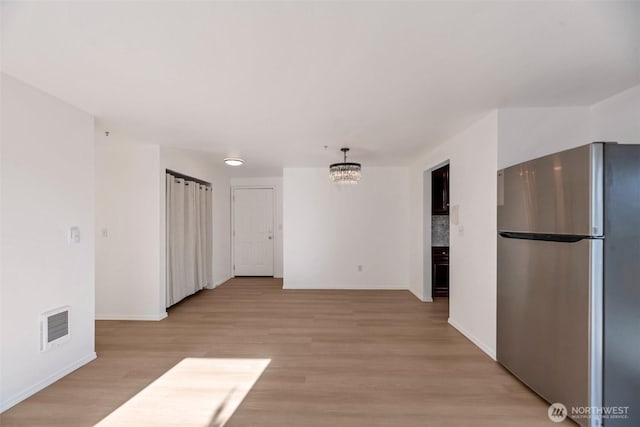 12050 15th Ave NE Unit 404, Seattle, WA 98125 - empty room featuring light wood-style flooring, a chandelier, and baseboards