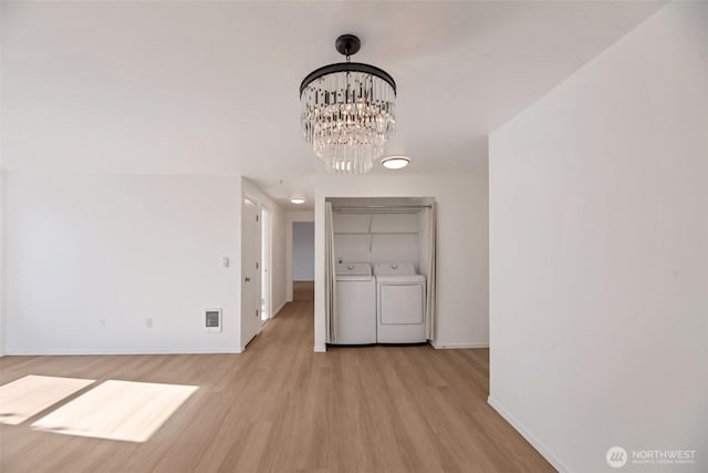 12050 15th Ave NE Unit 404, Seattle, WA 98125 - unfurnished dining area featuring light wood-type flooring, baseboards, washer and dryer, and a chandelier