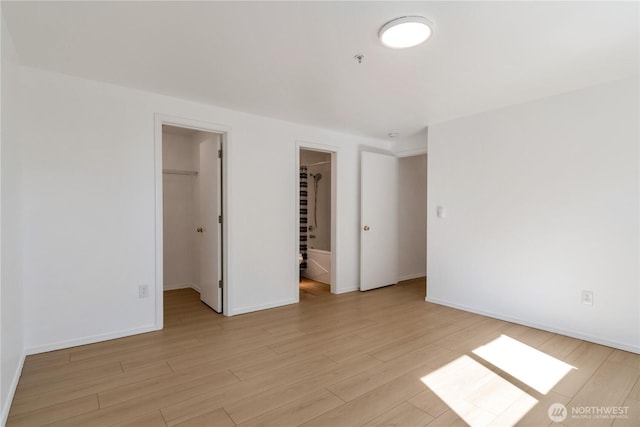 12050 15th Ave NE Unit 404, Seattle, WA 98125 - unfurnished bedroom with a walk in closet, light wood-type flooring, a closet, and baseboards