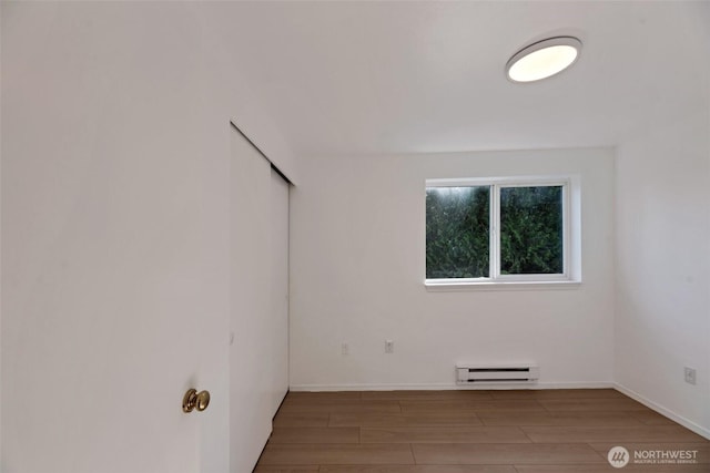 12050 15th Ave NE Unit 404, Seattle, WA 98125 - unfurnished room featuring a baseboard heating unit, wood finished floors, and baseboards