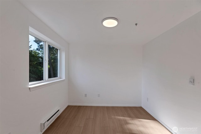 12050 15th Ave NE Unit 404, Seattle, WA 98125 - spare room with a baseboard radiator, wood finished floors, and baseboards