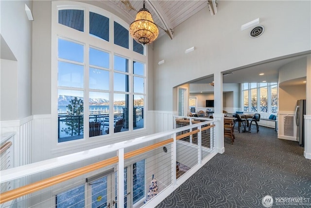 1350 W Woodin Ave, Chelan, WA 98816 - hallway with wainscoting, a chandelier, a towering ceiling, dark carpet, and beam ceiling