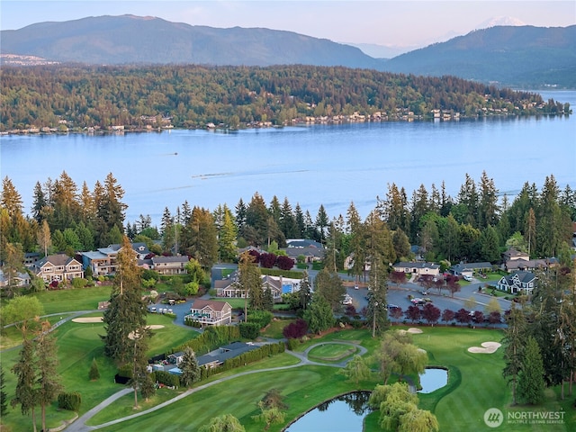 aerial view of property and surrounding area with a water and mountain view, a golf club, and a heavily wooded area