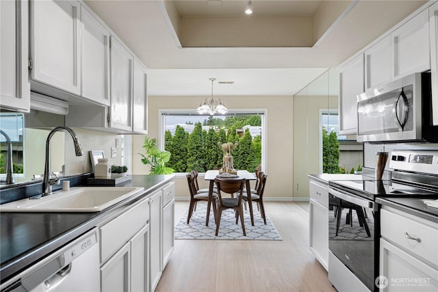 9201 NE Juanita Dr Unit 205, Kirkland, WA 98034 - kitchen featuring appliances with stainless steel finishes, a sink, light wood-style flooring, a chandelier, and white cabinets