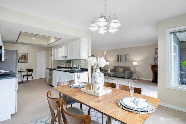 9201 NE Juanita Dr Unit 205, Kirkland, WA 98034 - dining area with a raised ceiling, light wood-style flooring, baseboards, and a chandelier