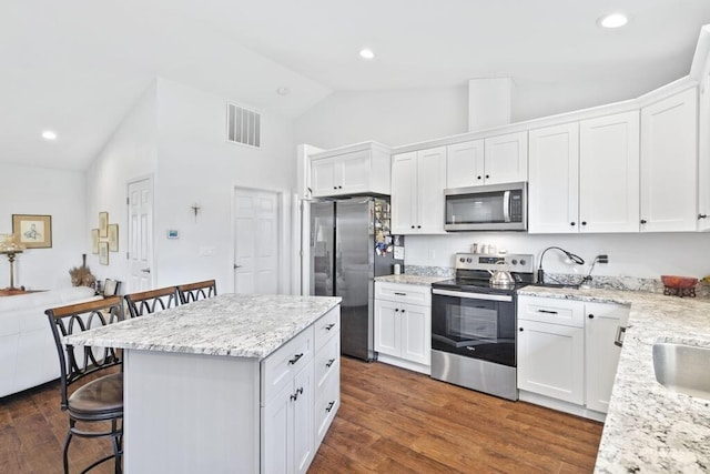 6 SE 16th St, Chehalis, WA 98532 - kitchen with high vaulted ceiling, a kitchen breakfast bar, white cabinets, dark wood-type flooring, and appliances with stainless steel finishes