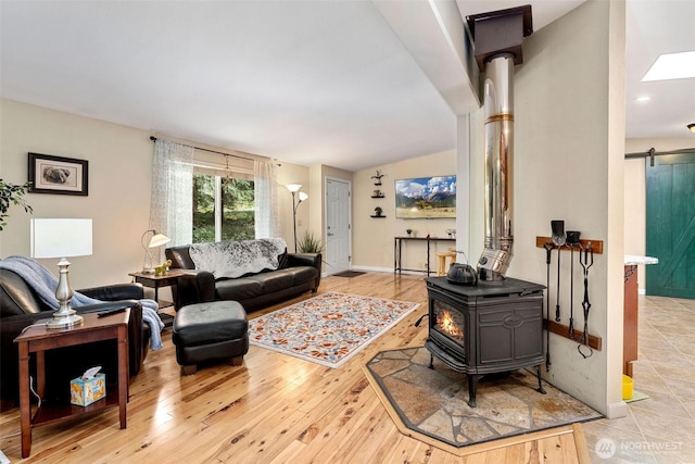 26911 312th Ave SE, Ravensdale, WA 98051 - living room with a wood stove, light wood finished floors, a barn door, and vaulted ceiling