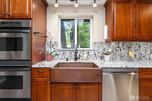 26911 312th Ave SE, Ravensdale, WA 98051 - kitchen with a sink, stainless steel appliances, brown cabinetry, rail lighting, and decorative backsplash