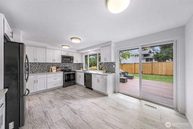 12219 SE 64th Pl, Bellevue, WA 98006 - kitchen featuring stainless steel appliances, tasteful backsplash, light countertops, white cabinets, and light marble finish flooring