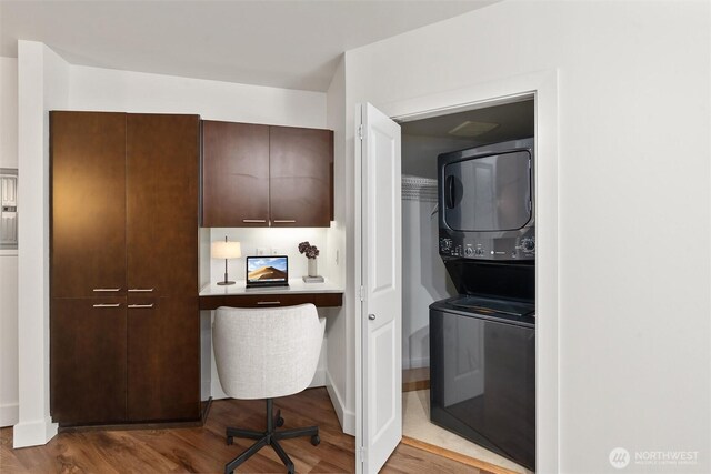 home office featuring stacked washer / drying machine and wood finished floors