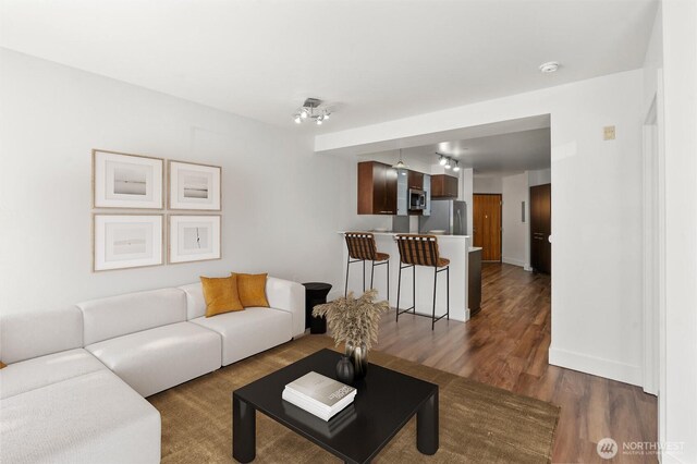 living area featuring baseboards and dark wood finished floors