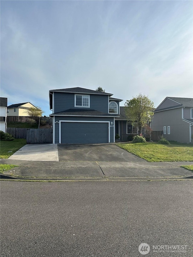 traditional home with an attached garage, concrete driveway, fence, and a front lawn