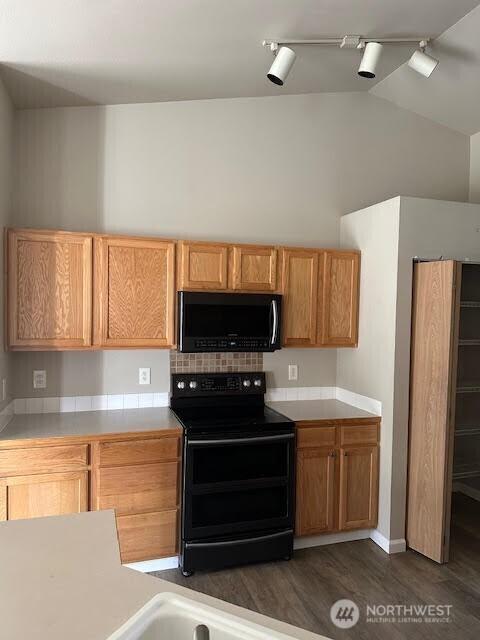 kitchen featuring black appliances, light countertops, dark wood-type flooring, and track lighting