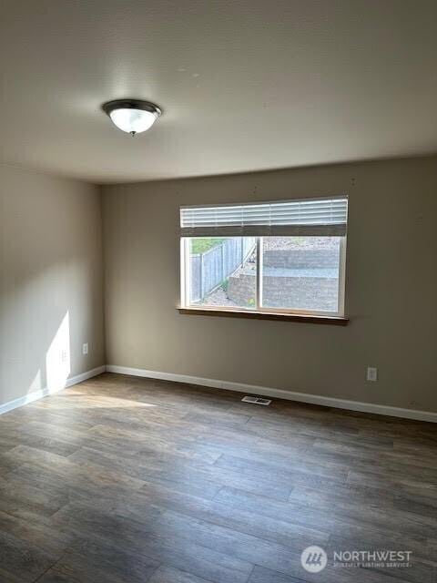 spare room featuring baseboards, visible vents, and wood finished floors
