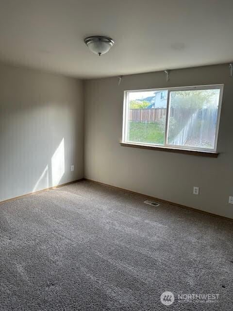 unfurnished room featuring baseboards, visible vents, and carpet