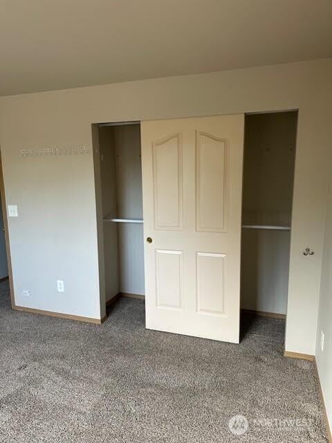 unfurnished bedroom with carpet floors, a closet, and baseboards