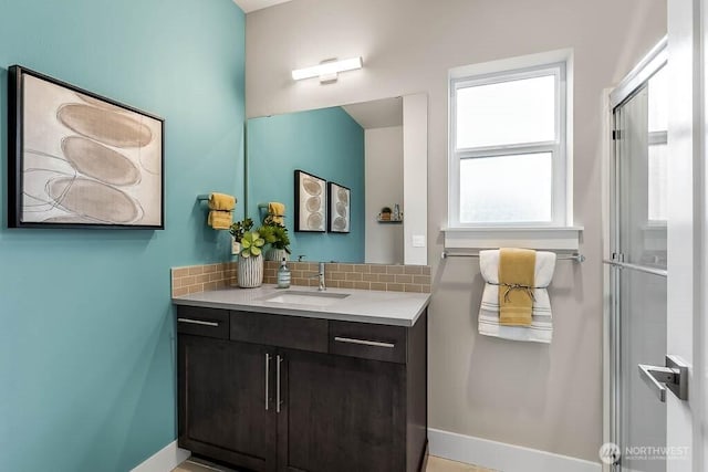 bathroom featuring a shower with door, vanity, backsplash, and baseboards