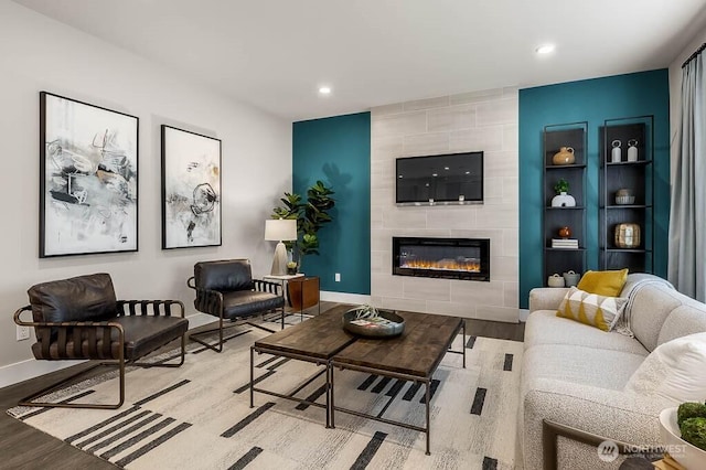 living room featuring a tiled fireplace, wood finished floors, baseboards, and recessed lighting