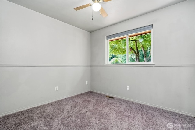 carpeted spare room with baseboards, a ceiling fan, and visible vents
