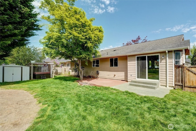 rear view of property featuring a storage shed, a yard, and fence