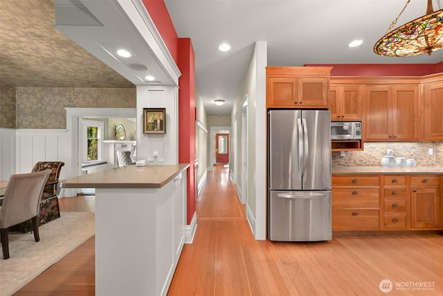 2234 Main St, Ferndale, WA 98248 - kitchen with stainless steel appliances, brown cabinets, light wood-type flooring, light countertops, and a wainscoted wall