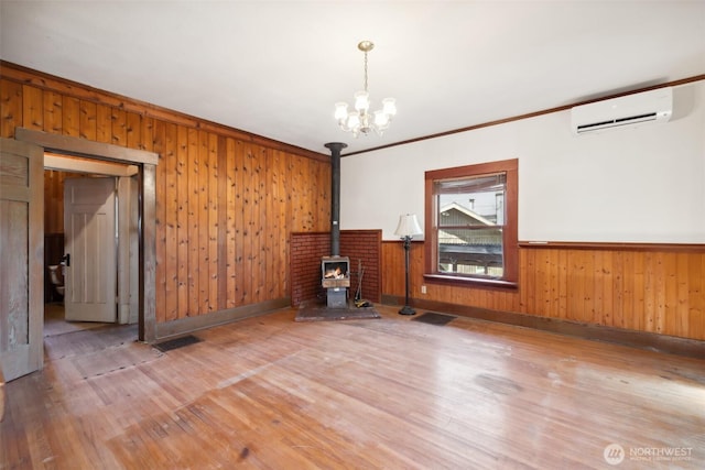 219 W 15th St, Port Angeles, WA 98362 - unfurnished room featuring a wood stove, a notable chandelier, a wall unit AC, and wood finished floors