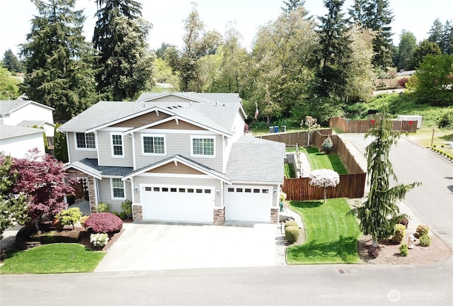view of front of home featuring driveway, fence, an attached garage, stone siding, and a front yard