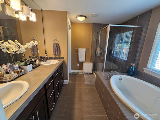 bathroom featuring a stall shower, a garden tub, and a sink