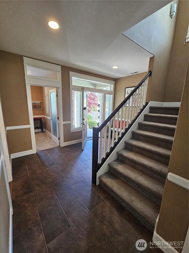foyer entrance featuring baseboards, stairway, and recessed lighting
