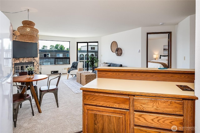 10601 Bagley Ave N Unit 204, Seattle, WA 98133 - kitchen featuring carpet flooring, a stone fireplace, open floor plan, light countertops, and brown cabinetry