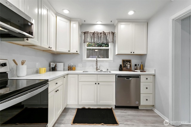 624 S Lawrence St, Tacoma, WA 98405 - kitchen featuring appliances with stainless steel finishes, a sink, light wood-style floors, white cabinets, and light countertops