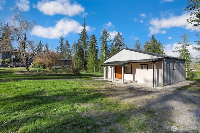 back of property featuring a lawn, metal roof, and a standing seam roof