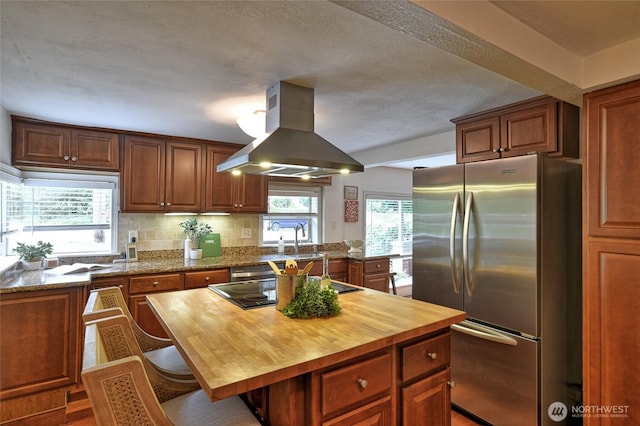 10733 14th Ave NE, Seattle, WA 98125 - kitchen with freestanding refrigerator, island range hood, butcher block countertops, black electric stovetop, and a kitchen breakfast bar