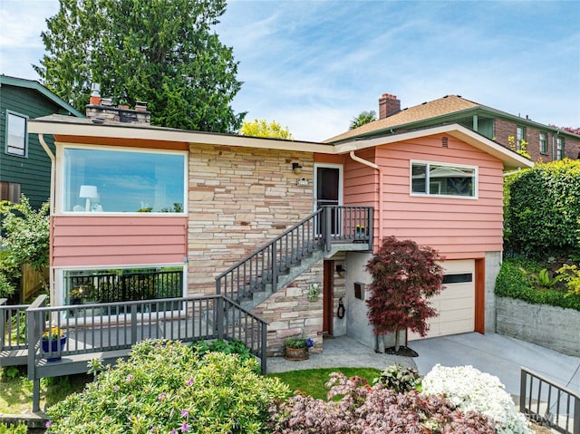 2537 Montavista Pl W, Seattle, WA 98199 - view of front of home with a chimney, an attached garage, driveway, stairs, and stone siding