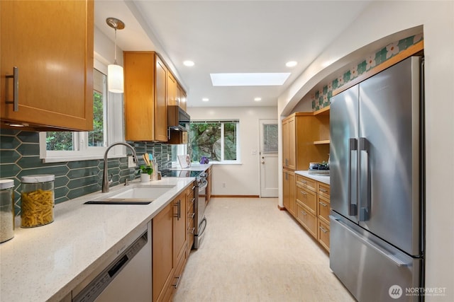 2537 Montavista Pl W, Seattle, WA 98199 - kitchen featuring stainless steel appliances, a skylight, a sink, decorative backsplash, and brown cabinets